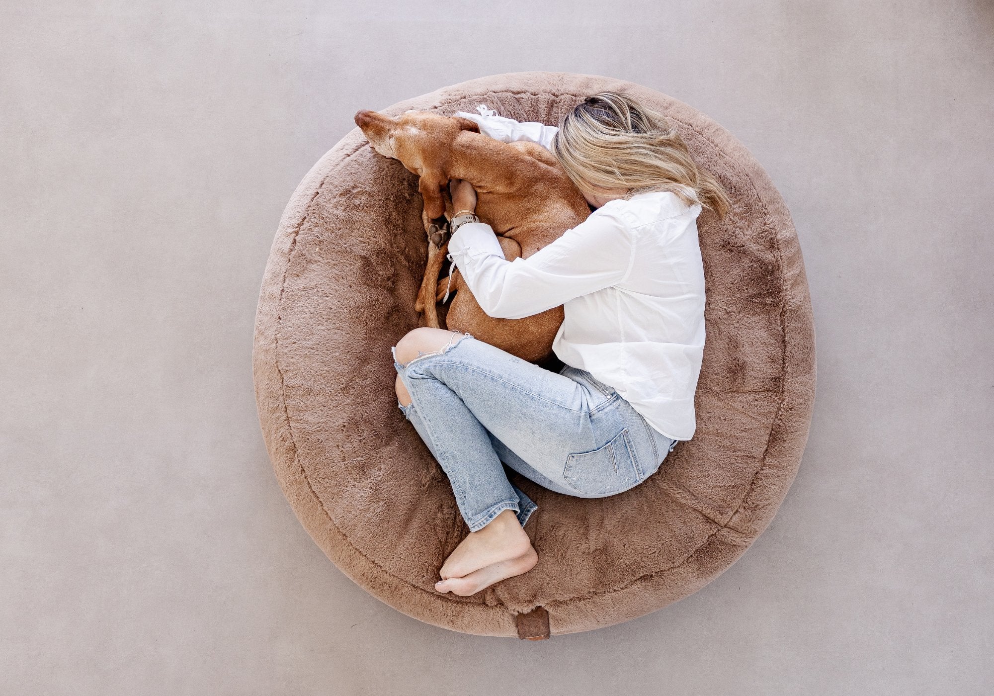 Frau kuschelt sich eng an ihren braunen Magyaur Vizsla Hund im extra großen maroon Hyggebed Original Hundebett