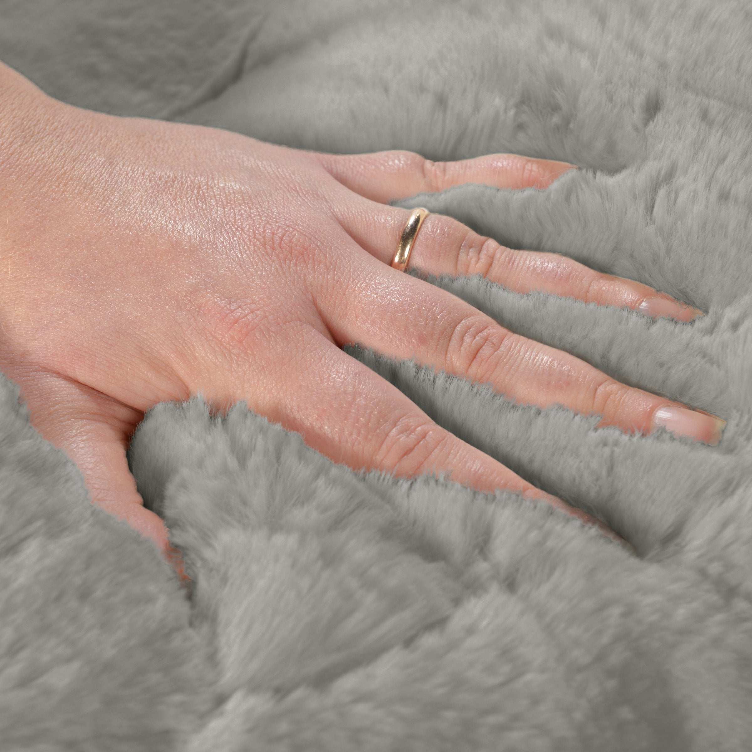 Eine Hand streicht durch den dichten, flauschigen und schadstofffreien Premium-Kuschelstoff des Hyggebeds in Stone Grau